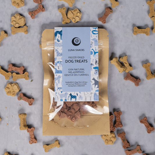 Package of Luna Snacks dog treats surrounded by bone-shaped treats on a gray background